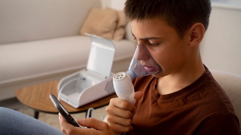 Menino adolescente controlando seu inalador por meio de uma aplicativo em seu celular para controlar a asma.
