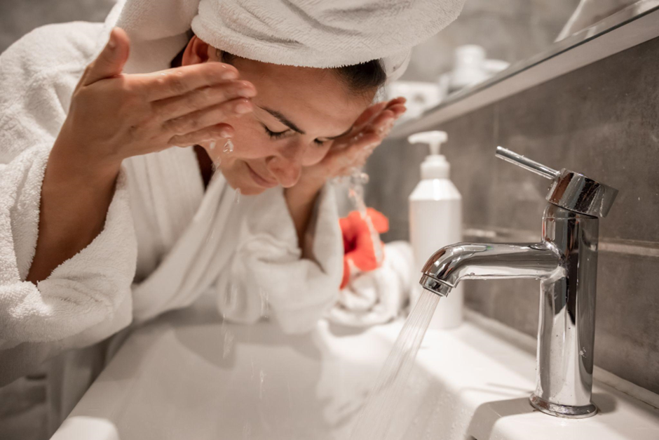 Mulher fazendo sua rotina de skincare à noite